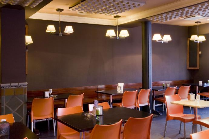A empty dimly lit restaurant dining area with Fabricmate Systems installed along the walls. The Fabric walls are a dark purple color.