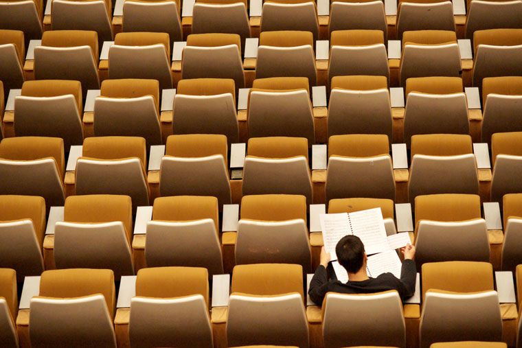 one person studying alone in large classroom 