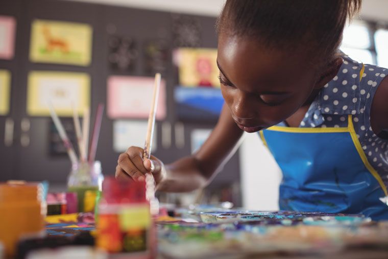 little girl smiles and paints - a classroom should inspire